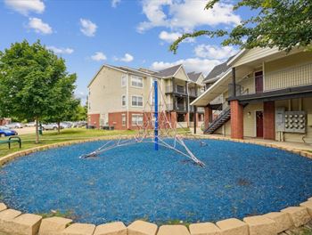 an outdoor pool with a swing set in front of an apartment building